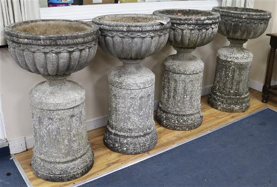 A set of four large cup shaped garden urns on fluted plinths (one a.f.) W.55cm approx.